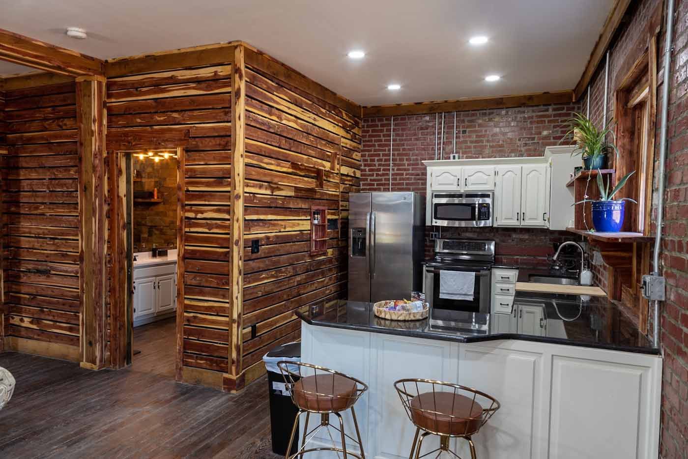 A kitchen with a refrigerator , microwave , sink and stools.