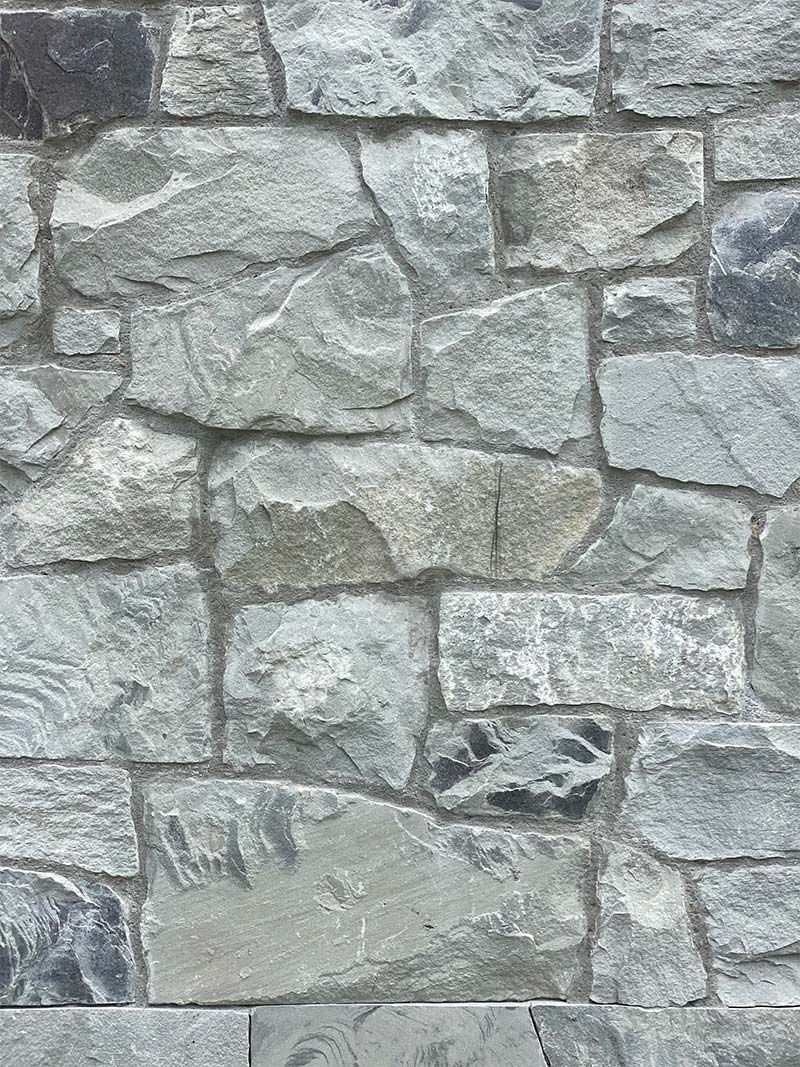 A close up of a stone wall with a lot of rocks on it.