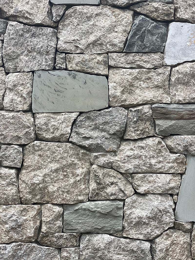 A close up of a stone wall made of different types of rocks.
