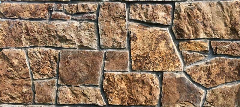 A close up of a stone wall with a brick pattern.