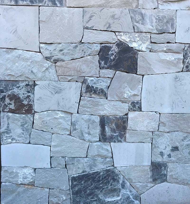 A close up of a stone wall with a variety of stones