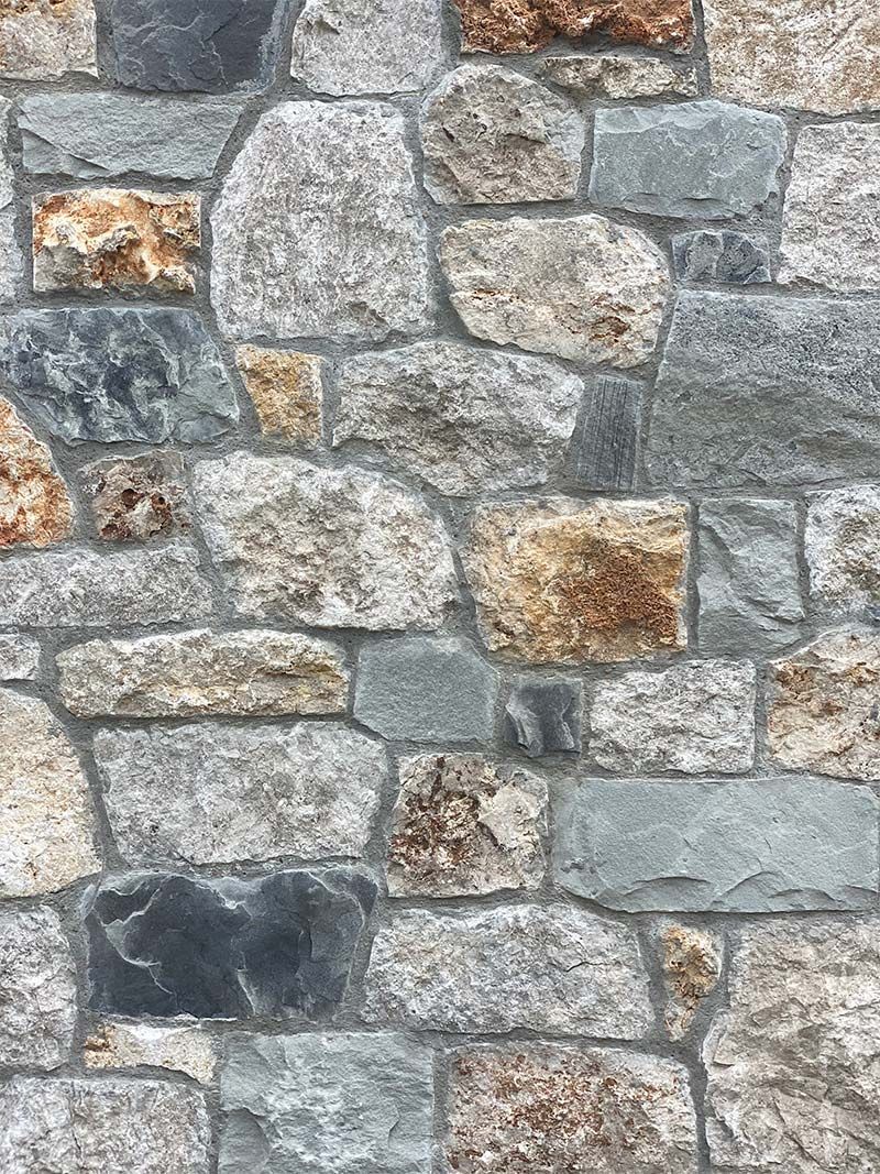 A close up of a stone wall with a brick pattern.