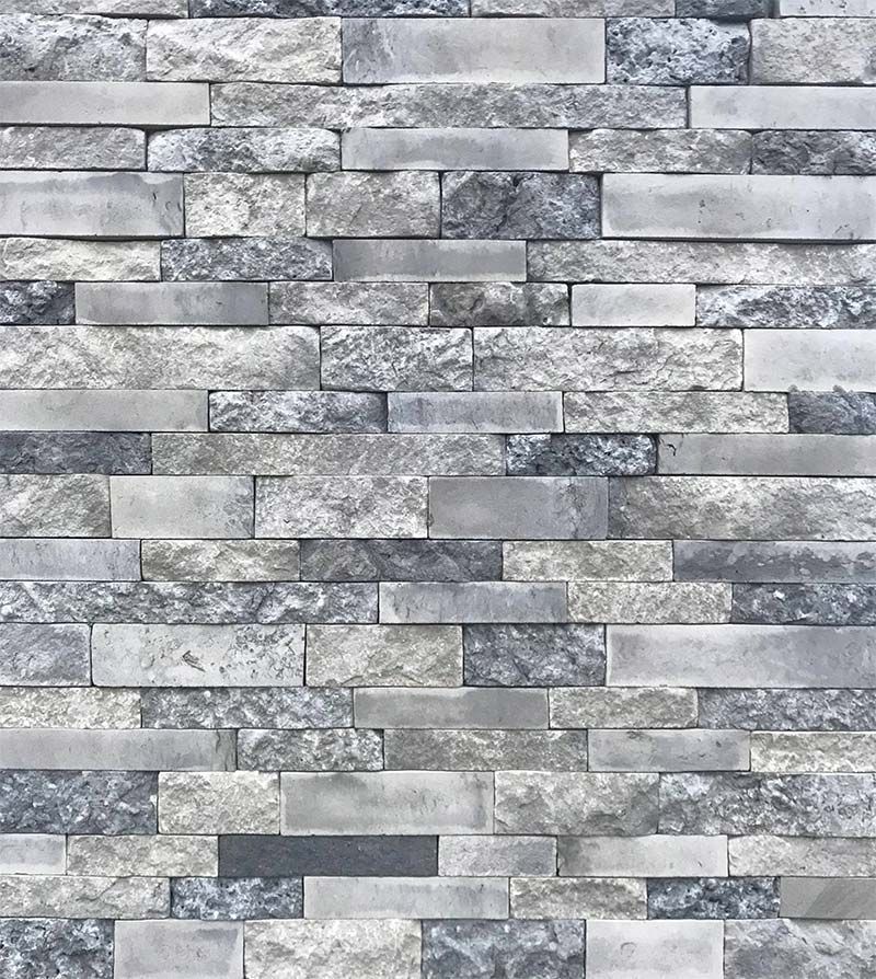 A close up of a brick wall made of gray and black bricks.