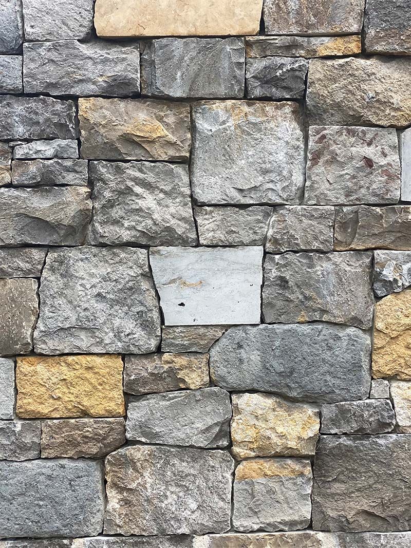 A close up of a stone wall with a lot of different colored bricks.