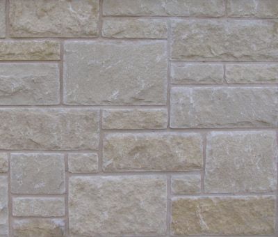 A close up of a stone wall with a brick pattern.