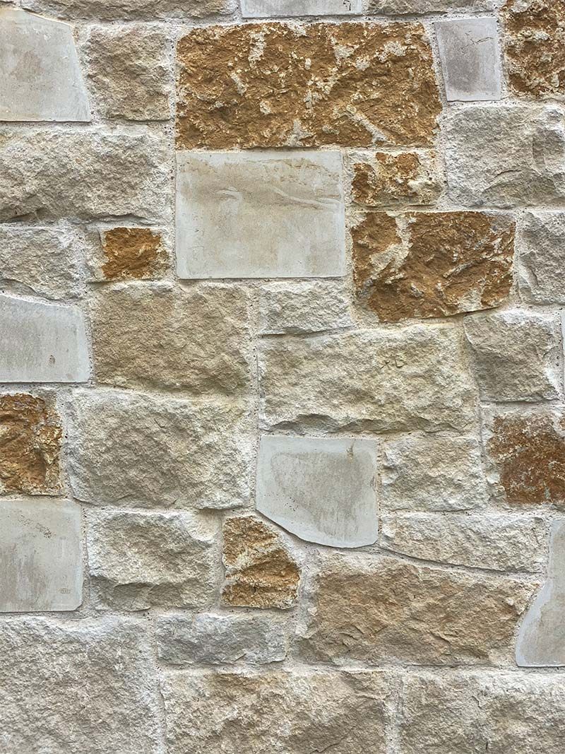 A close up of a stone wall with brown and white bricks.