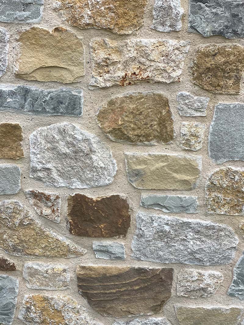 A close up of a stone wall with a lot of different colored rocks.