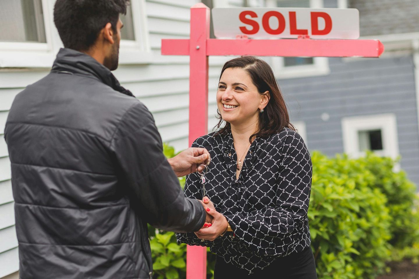 New Homeowner Receiving Keys Beside Sold Sign