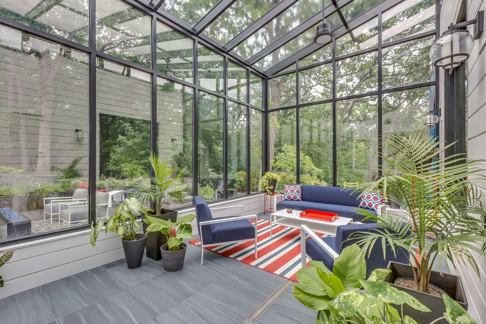 A sun room with a couch , chairs , and plants.