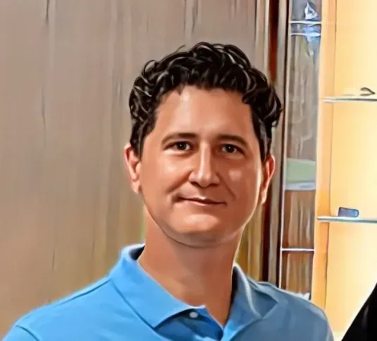 A man in a blue shirt is smiling for the camera.