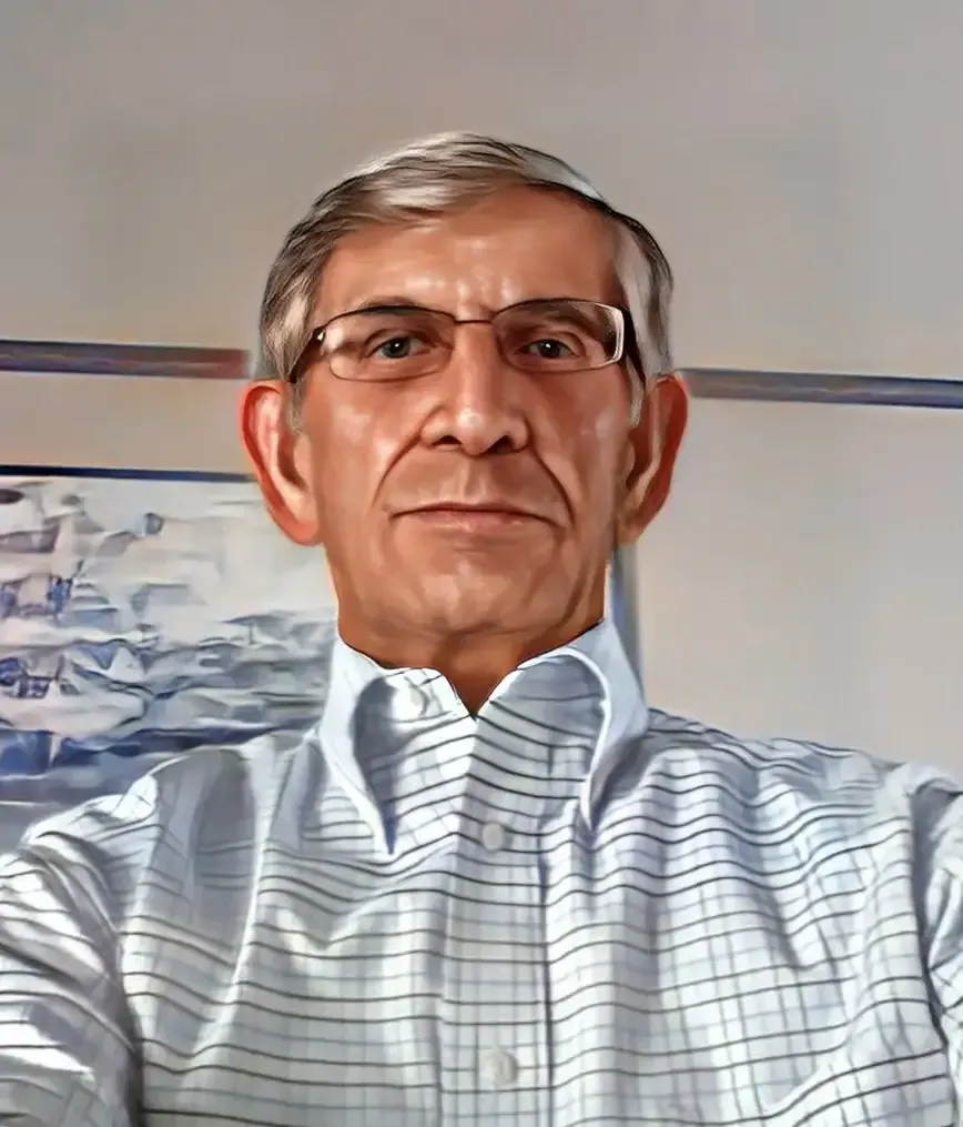 A man wearing glasses and a plaid shirt is taking a selfie.