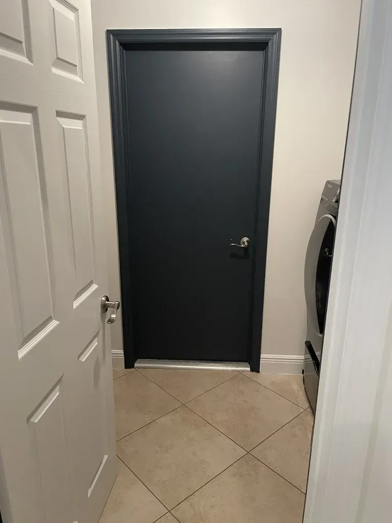 Hallway with dark gray door, white closet doors, and tiled floor