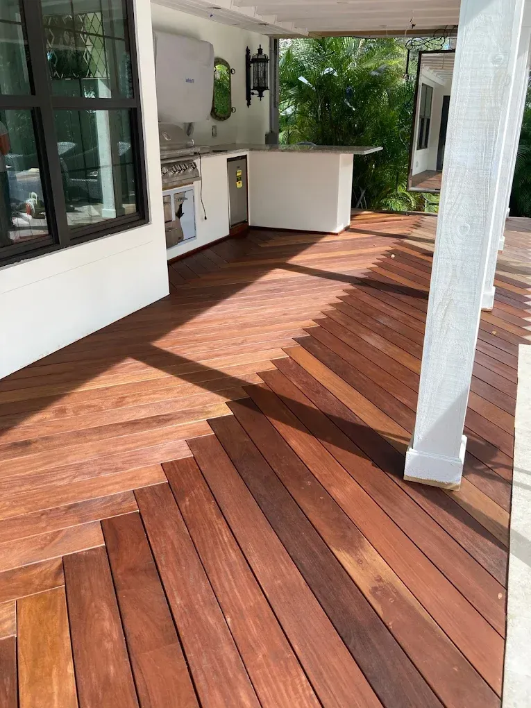 Wooden deck patio with a white outdoor kitchen and sunlight casting long shadows