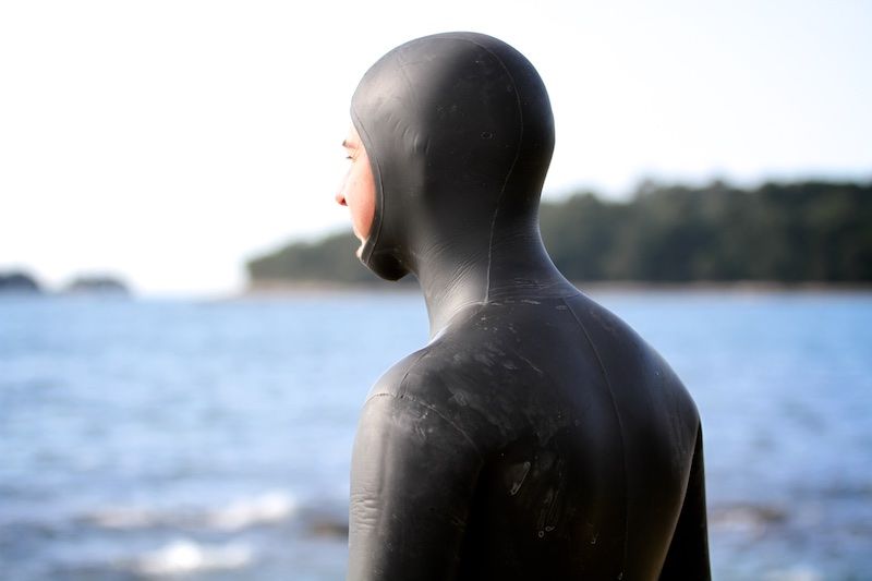 Un uomo con una muta è in piedi di fronte all'oceano.