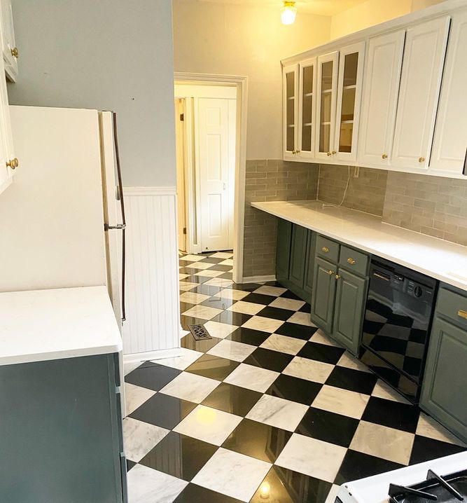 A kitchen with a checkered floor and white cabinets