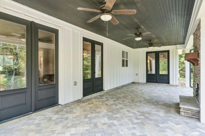 A large porch with a ceiling fan and a fireplace.