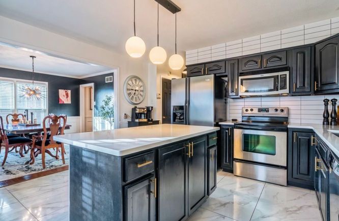 A kitchen with black cabinets and stainless steel appliances