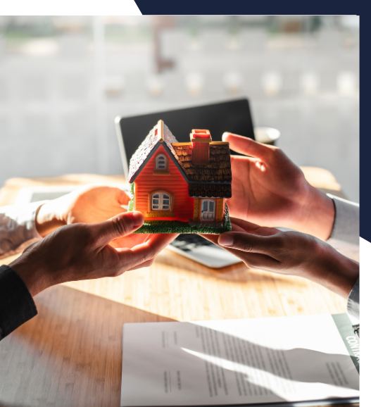 Two people are holding a small model house in their hands.