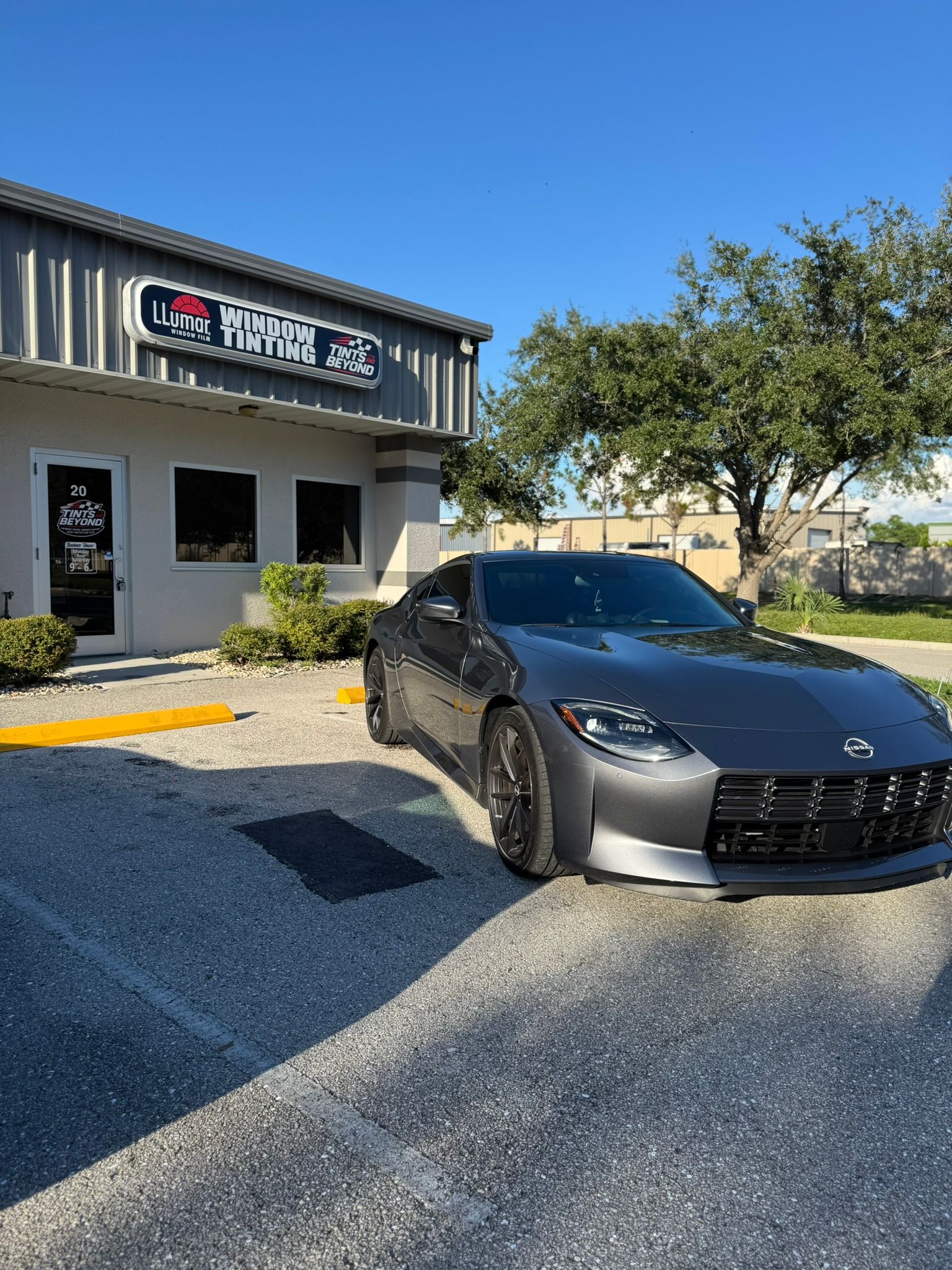 Black sports car parked outside a shop under a clear blue sky.