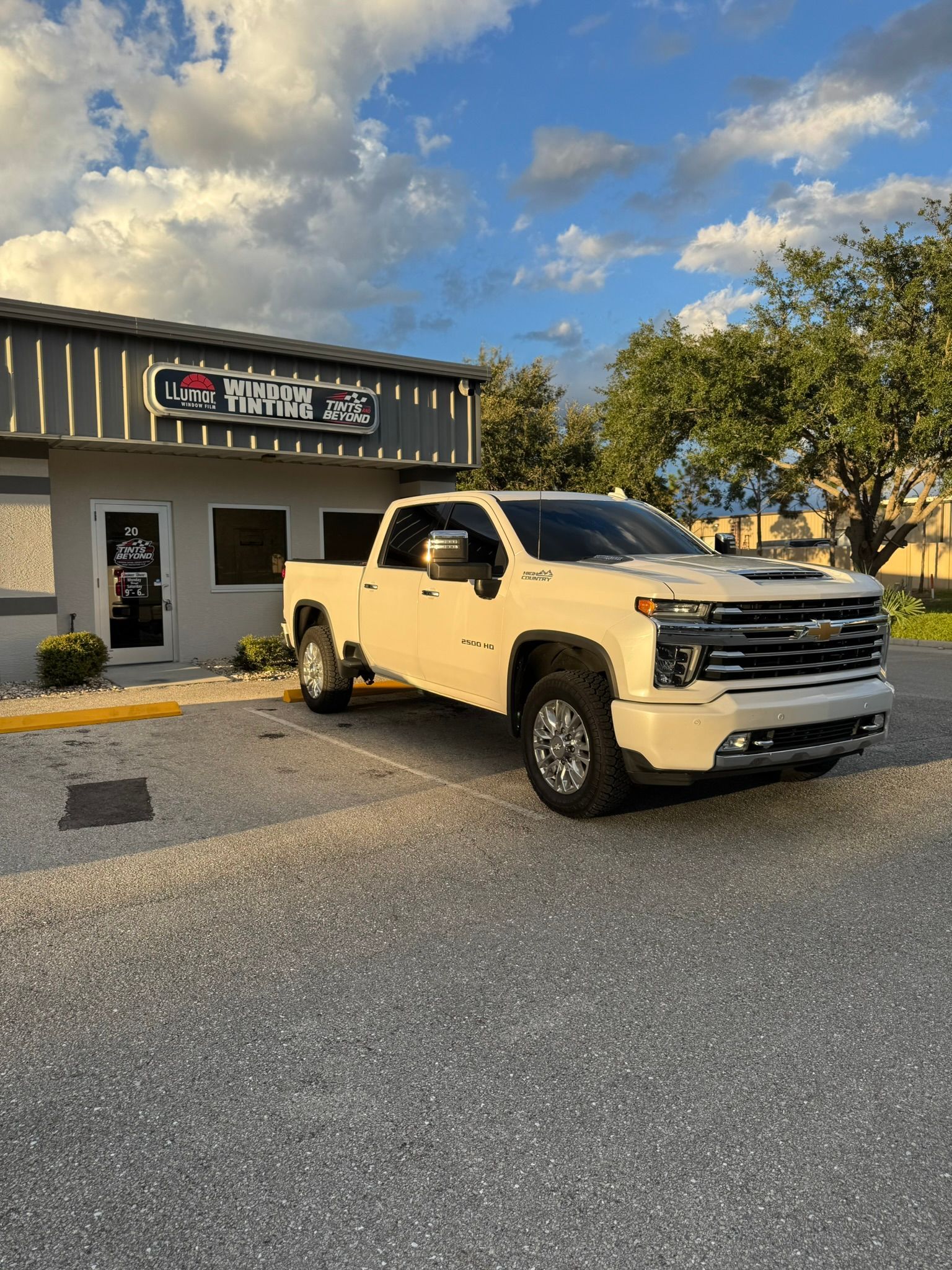 White pickup truck parked outside a storefront under a cloudy evening sky