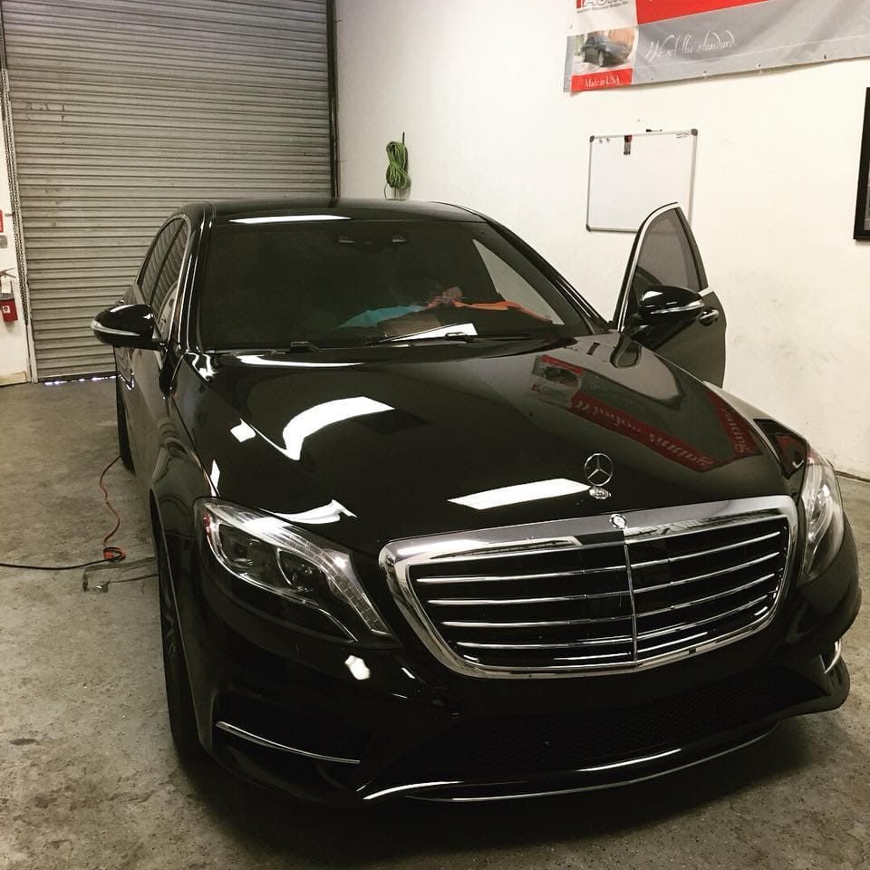 Black Mercedes sedan parked indoors with the driver’s door open.
