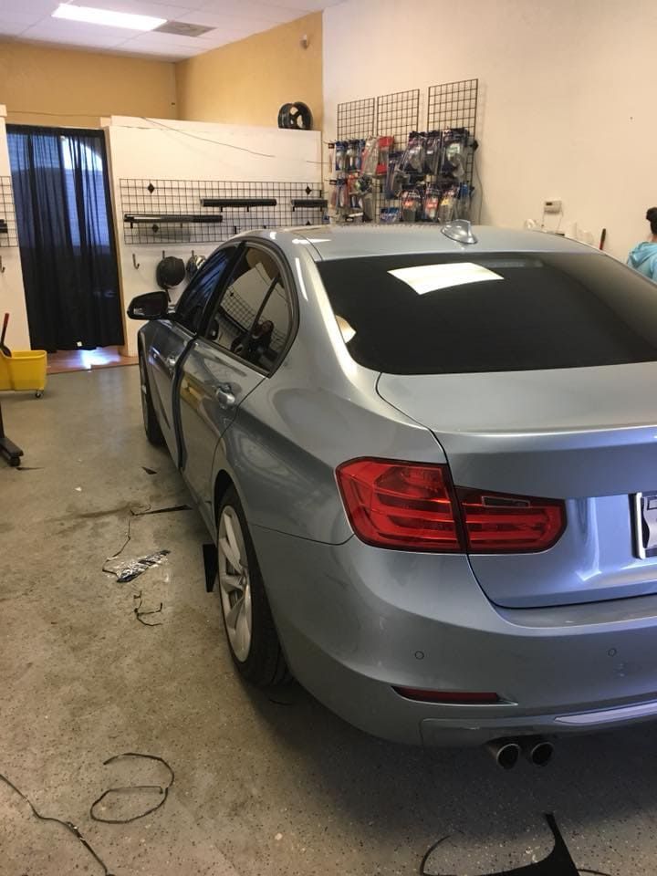 Gray sedan parked inside a garage with tools and equipment along the walls.