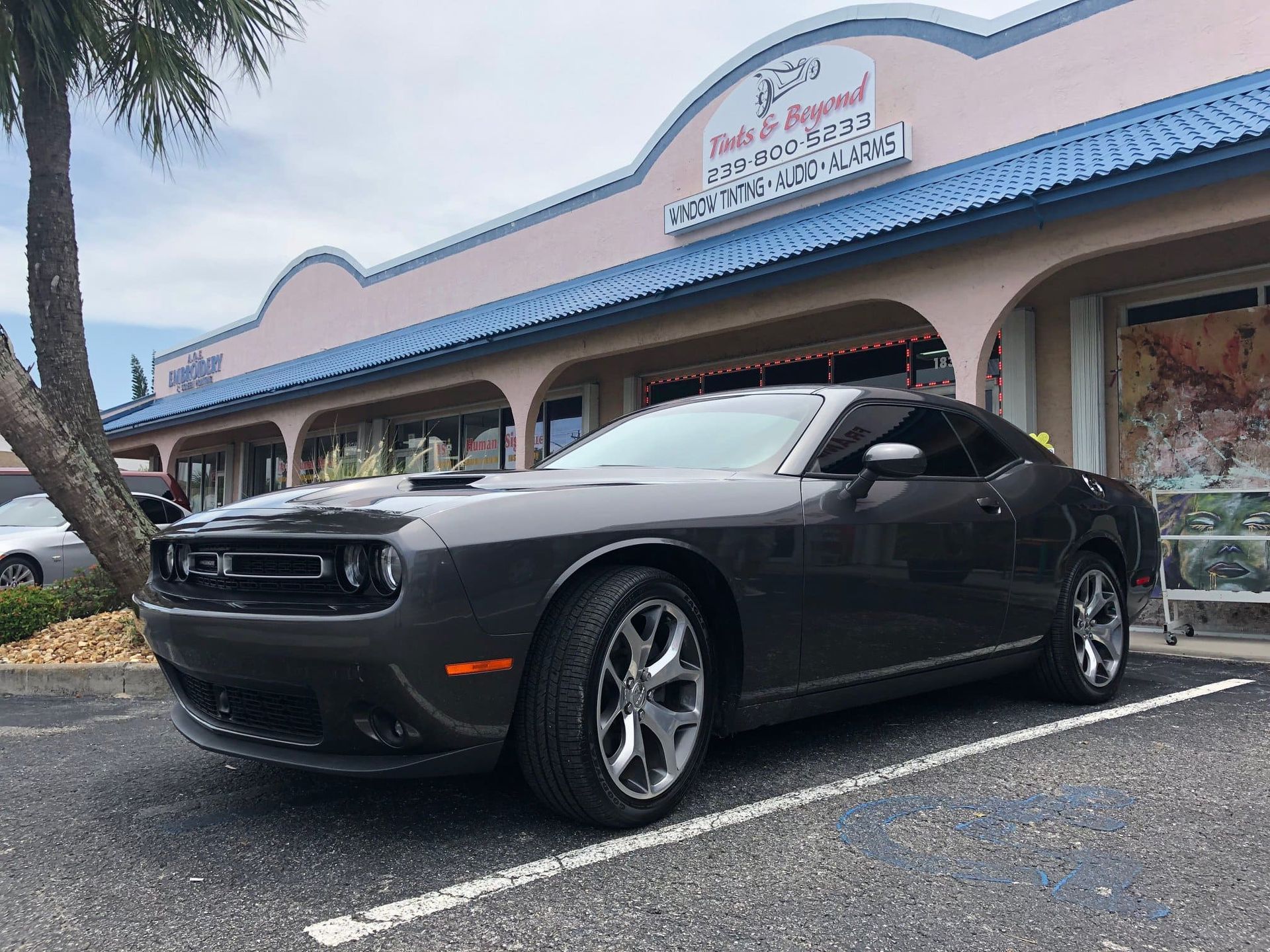 Black Dodge Challenger parked outside a storefront with a blue awning