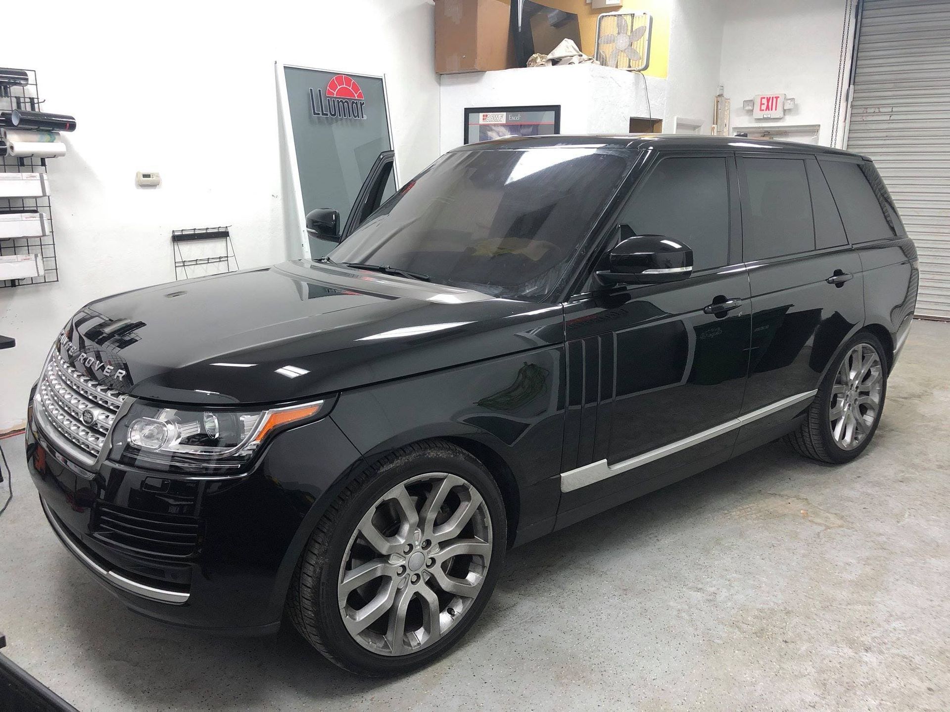 Black SUV parked in a garage, side view with chrome wheels and tinted windows