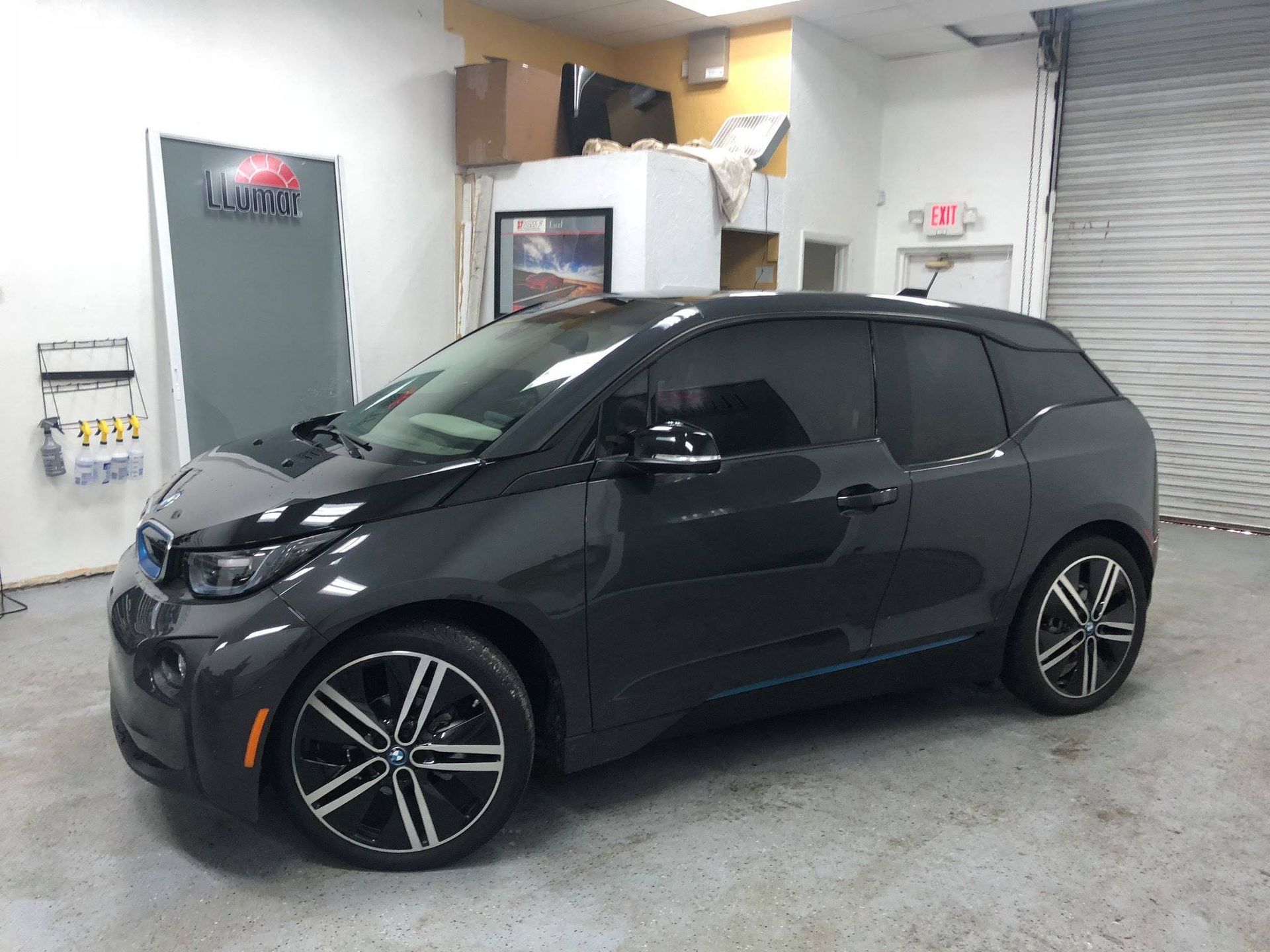 Black compact hatchback parked indoors in a garage with a white wall and roll-up door