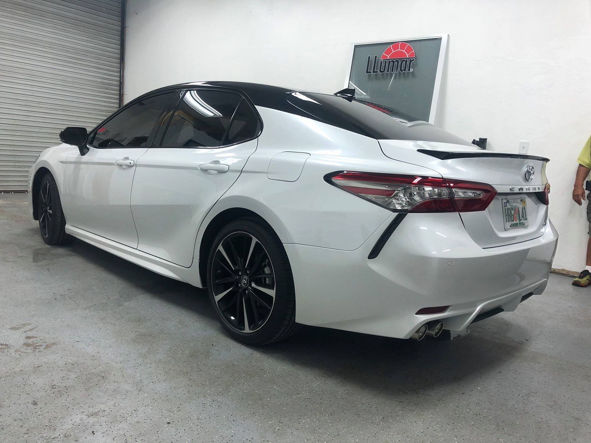 White sedan with black rims parked indoors in a garage