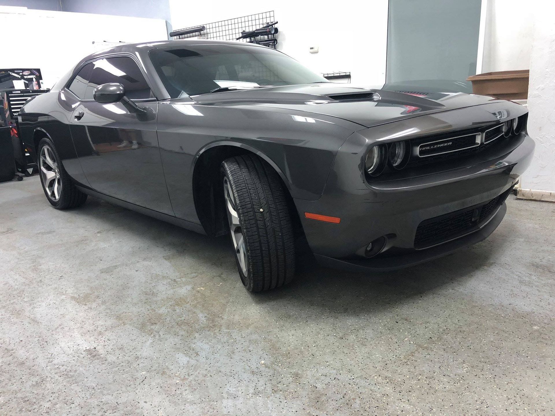Dark gray Dodge Challenger parked in a garage, viewed from the front-left side.