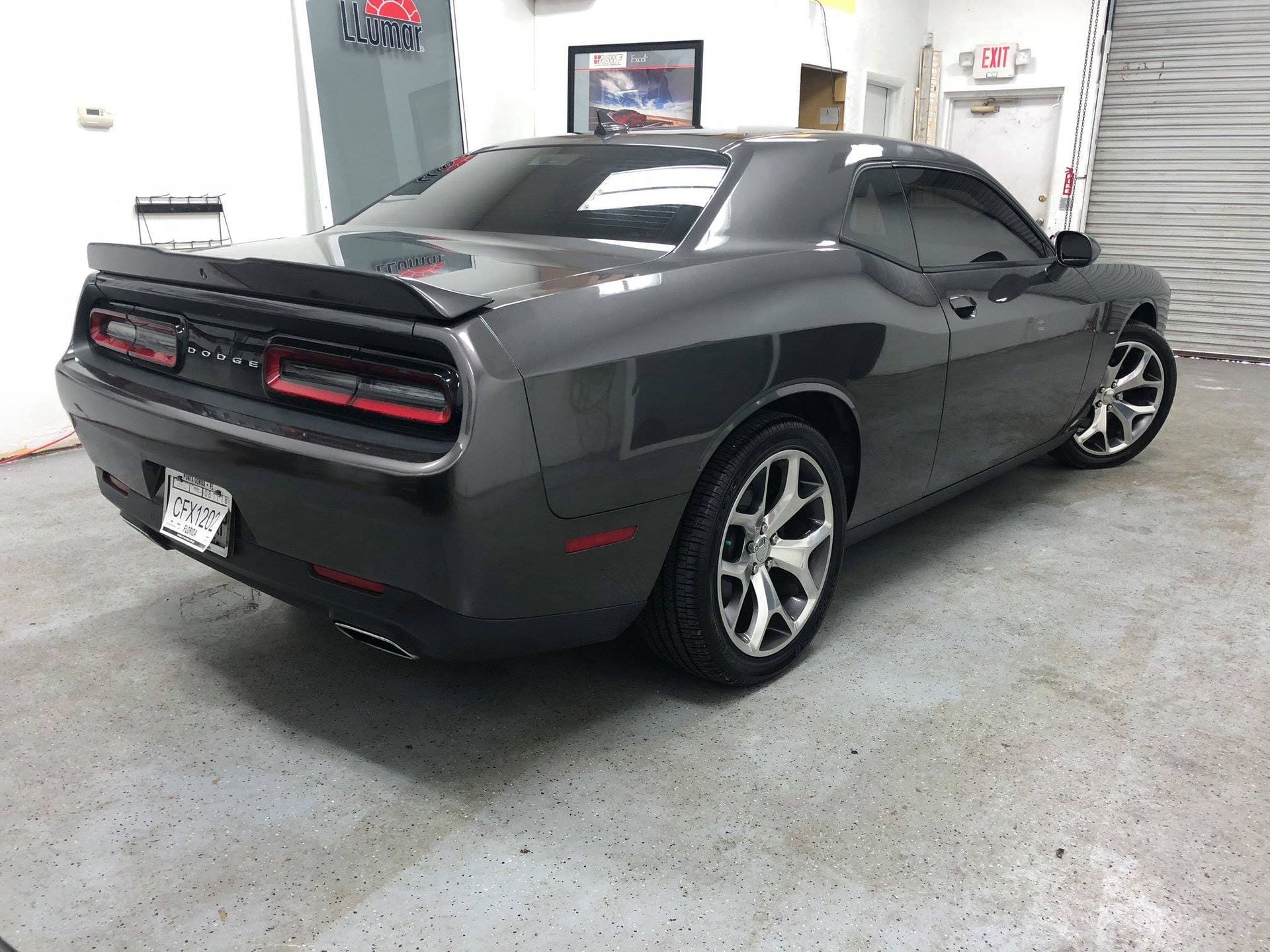 Gray Dodge Challenger parked indoors in a garage, rear three-quarter view.