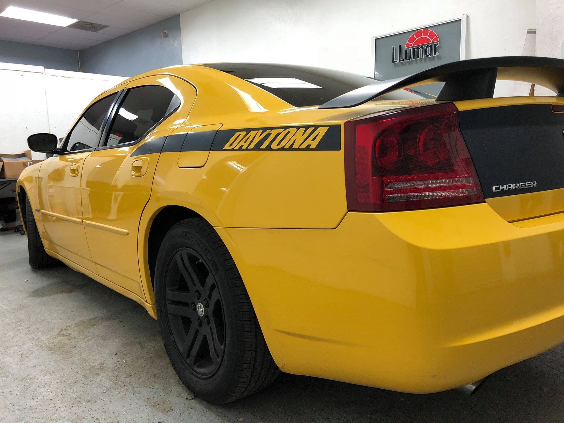 Yellow Dodge Daytona sports car parked indoors, rear three-quarter view.