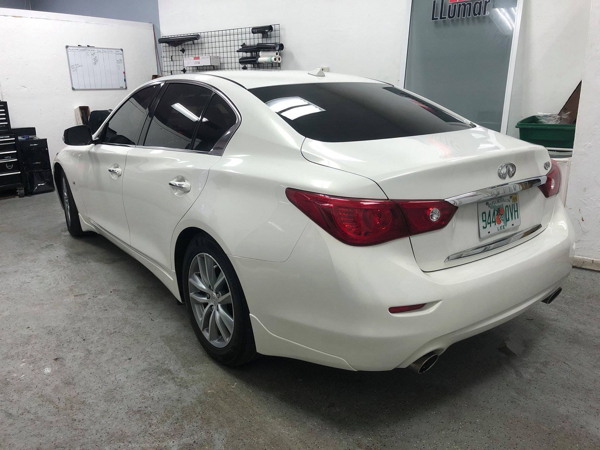 White sedan parked in a garage, rear three-quarter view