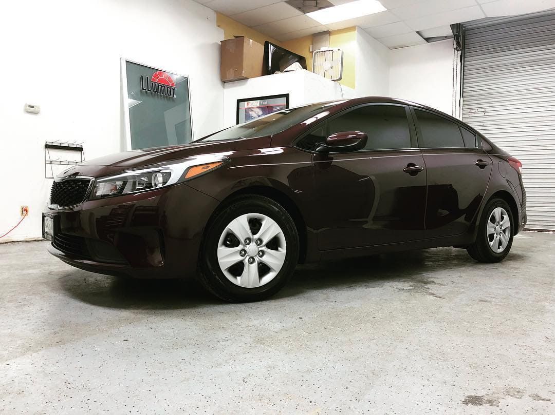 Dark sedan parked inside a garage with a concrete floor and white walls