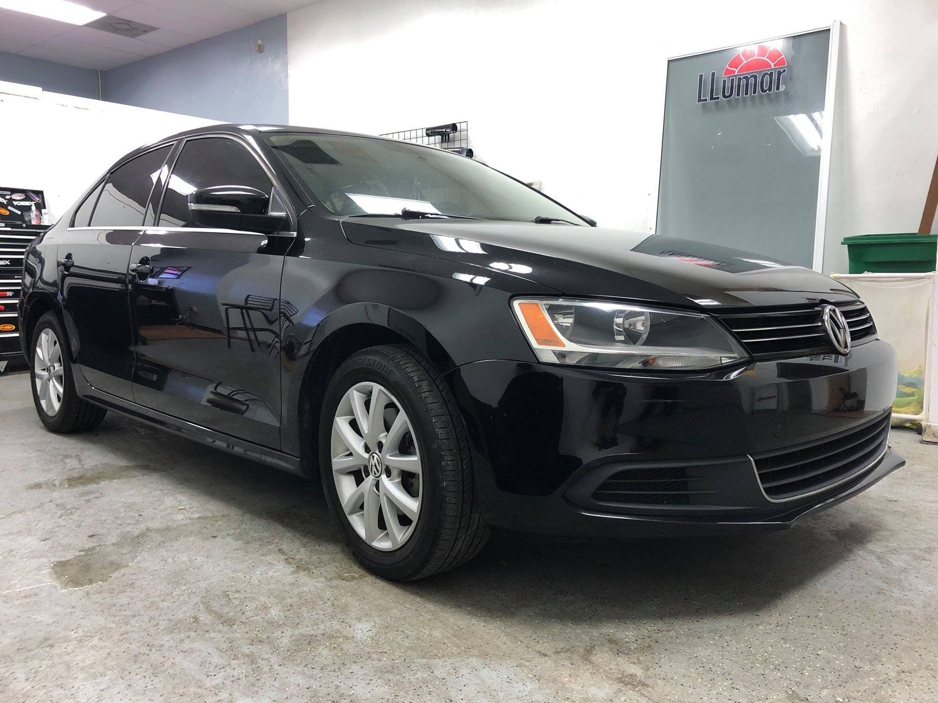 Black sedan parked indoors in a car dealership or service bay