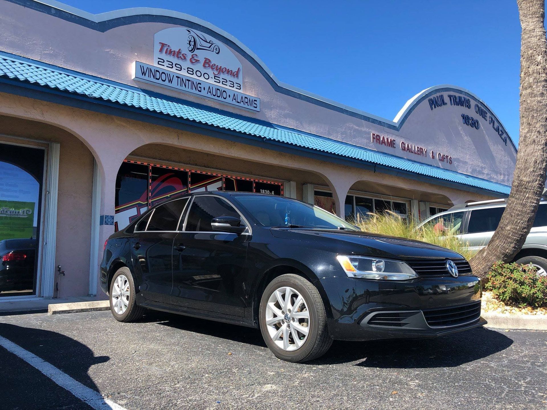 Black sedan parked outside a pastel storefront with blue roof and arched entrance