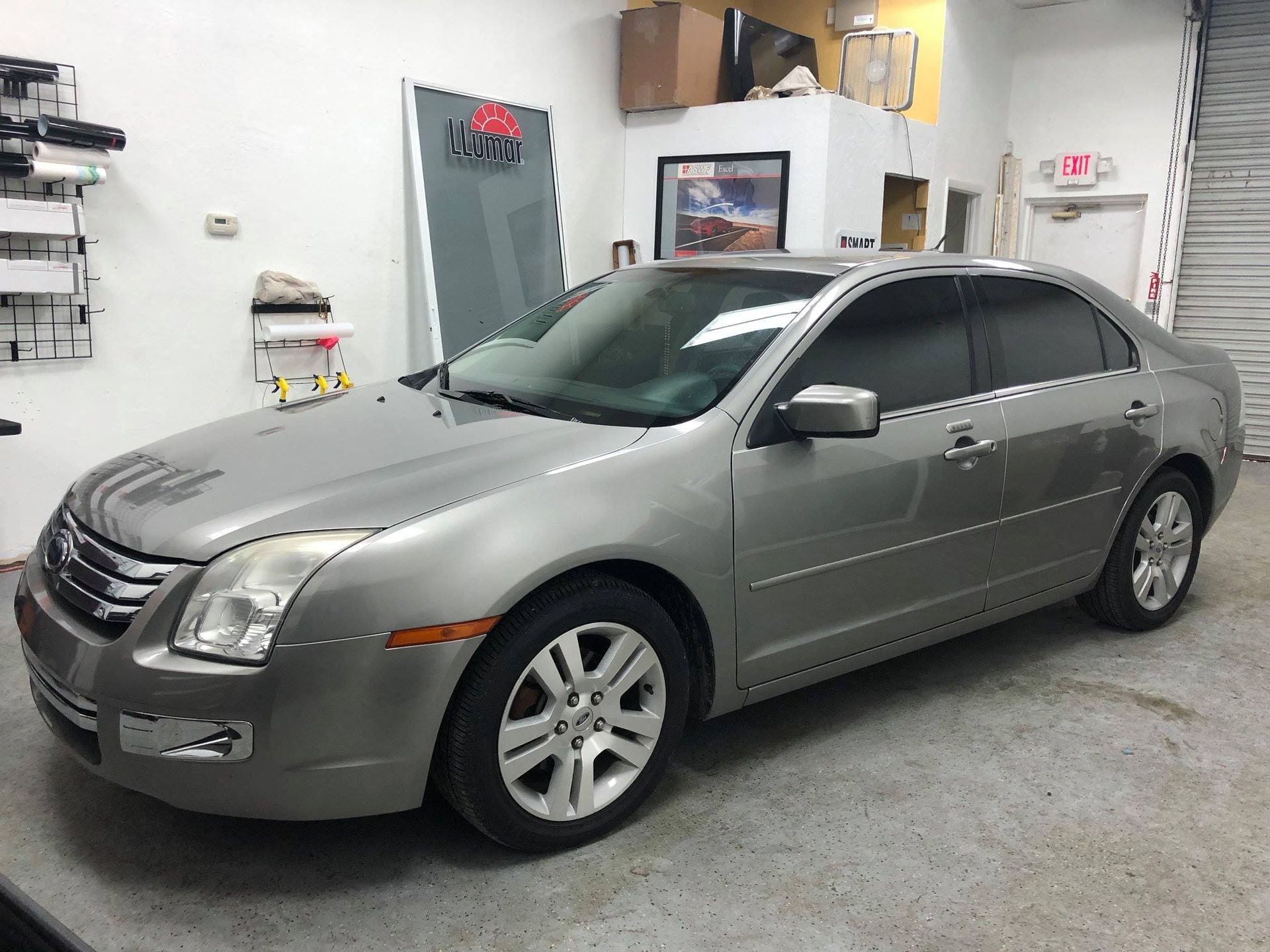 Silver sedan parked in a garage with tinted windows and visible front damage