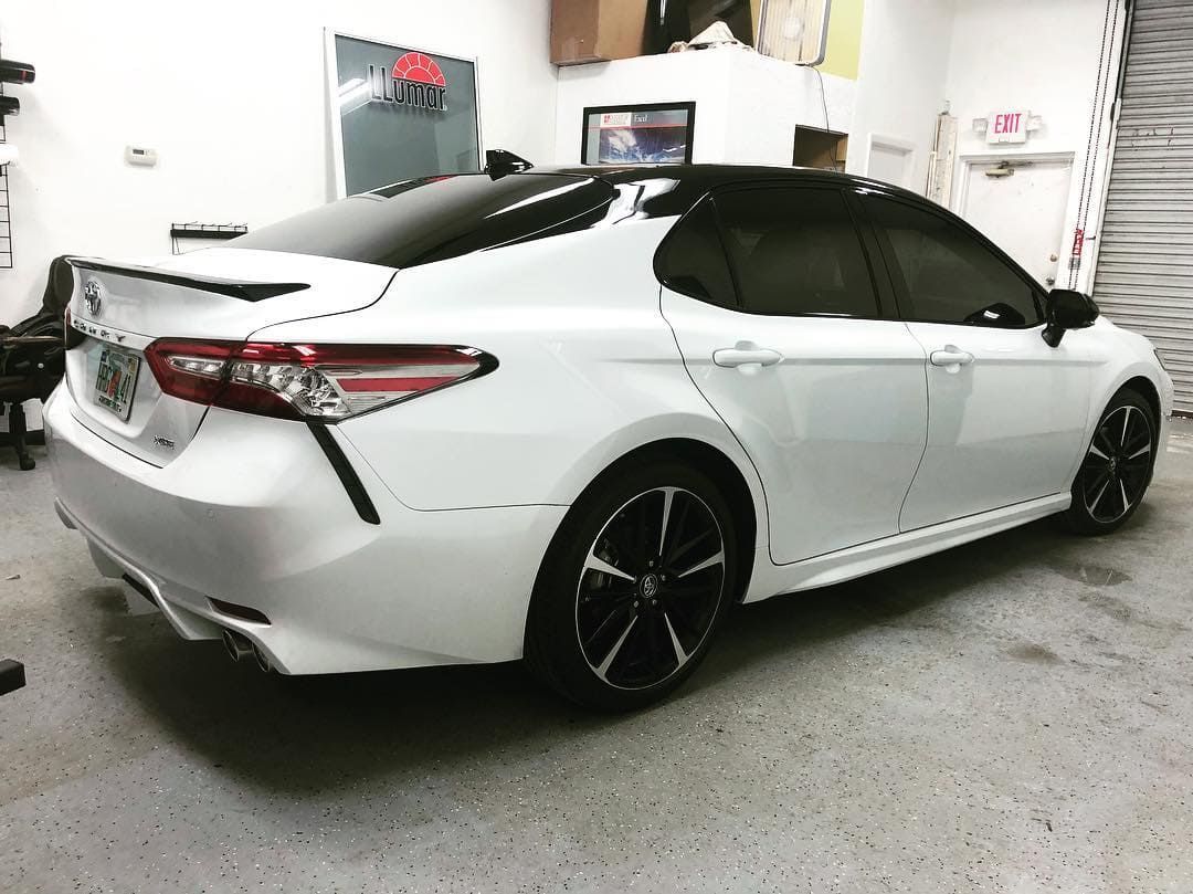 White sports sedan with black roof and rims parked in a garage