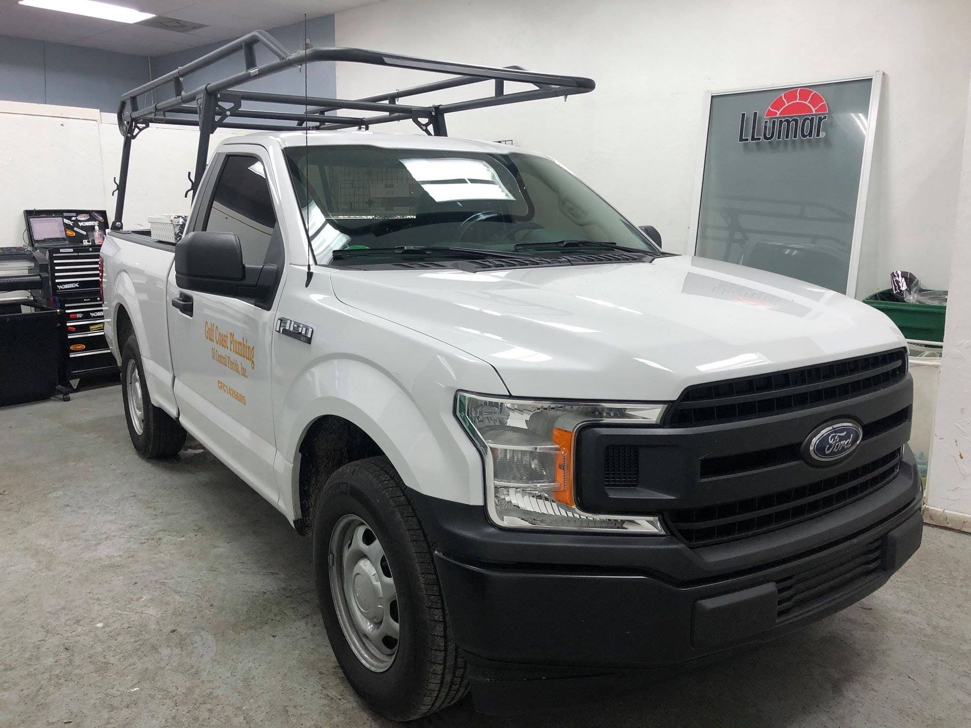 White Ford pickup with black utility rack parked in an indoor garage or workshop.