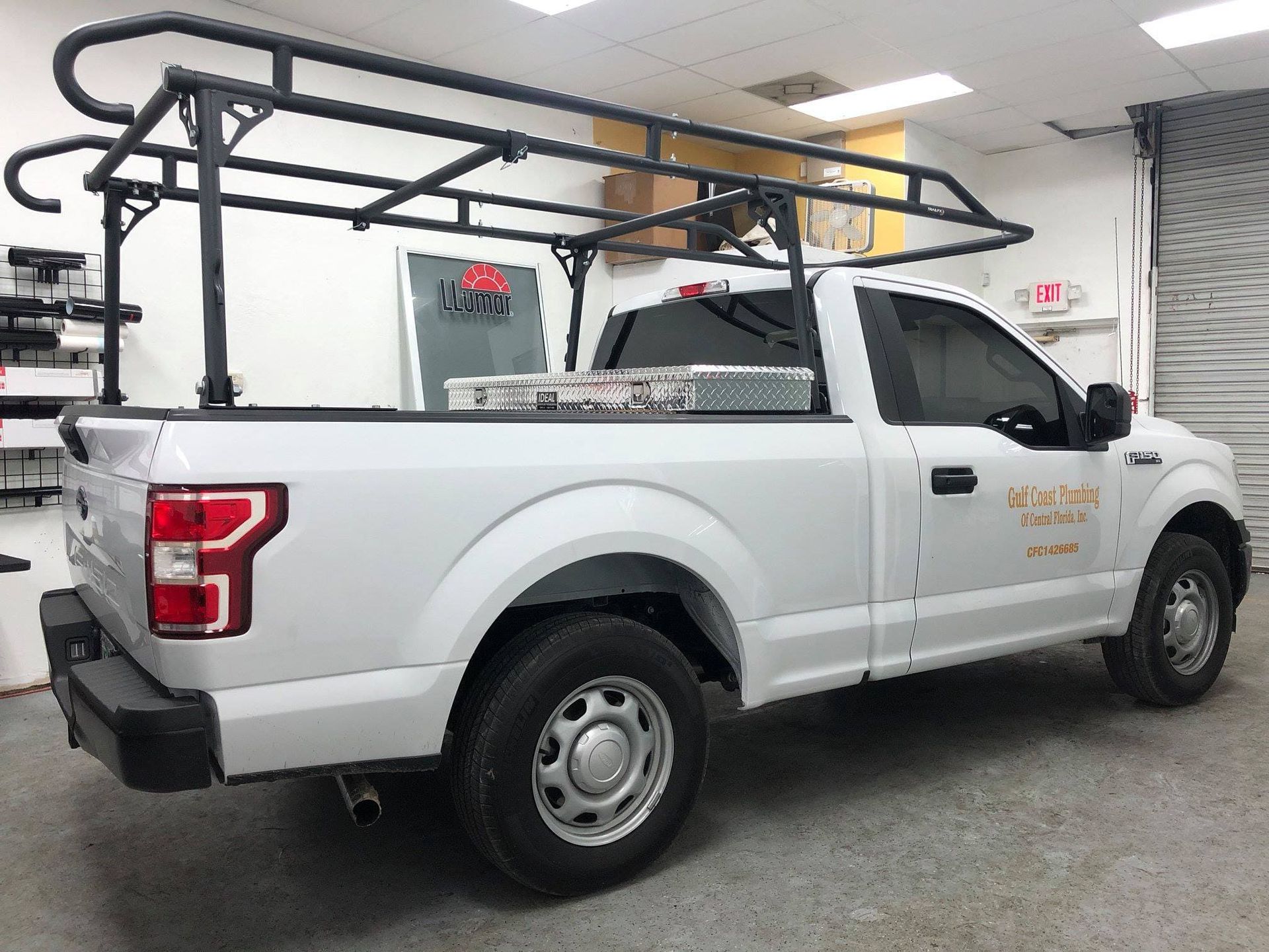 White pickup truck with black ladder rack parked indoors in a garage