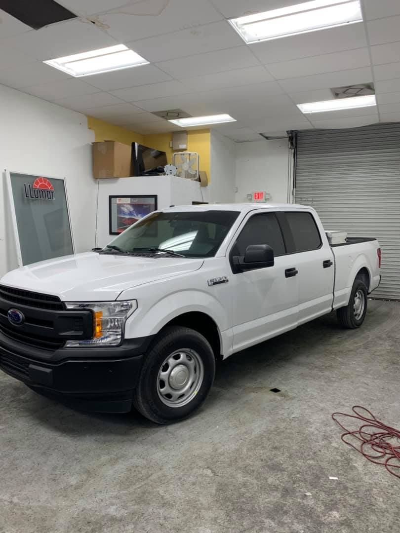 White Ford pickup truck parked inside a garage or workshop under bright ceiling lights