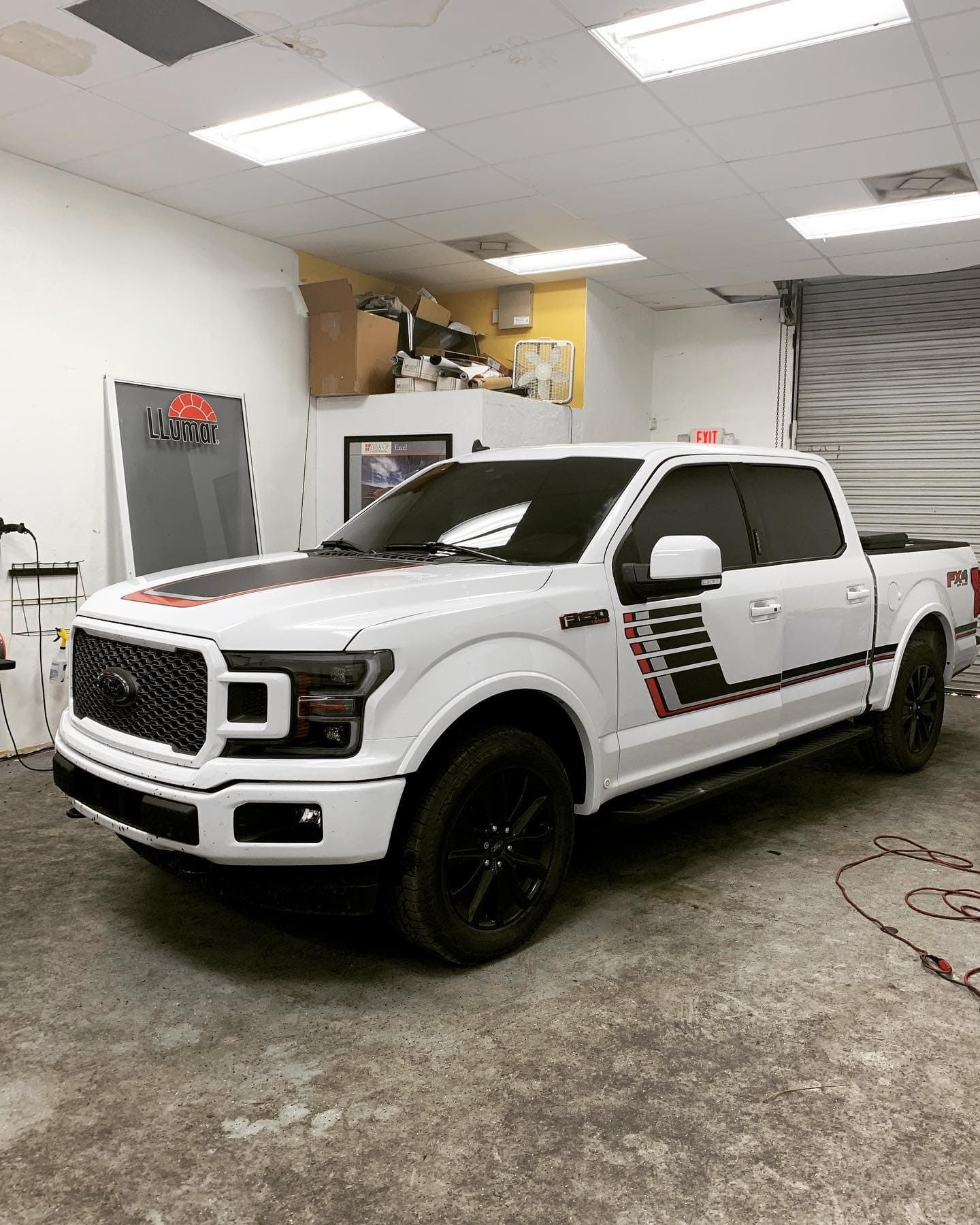 White lifted pickup truck with black wheels in an auto shop garage, side view.