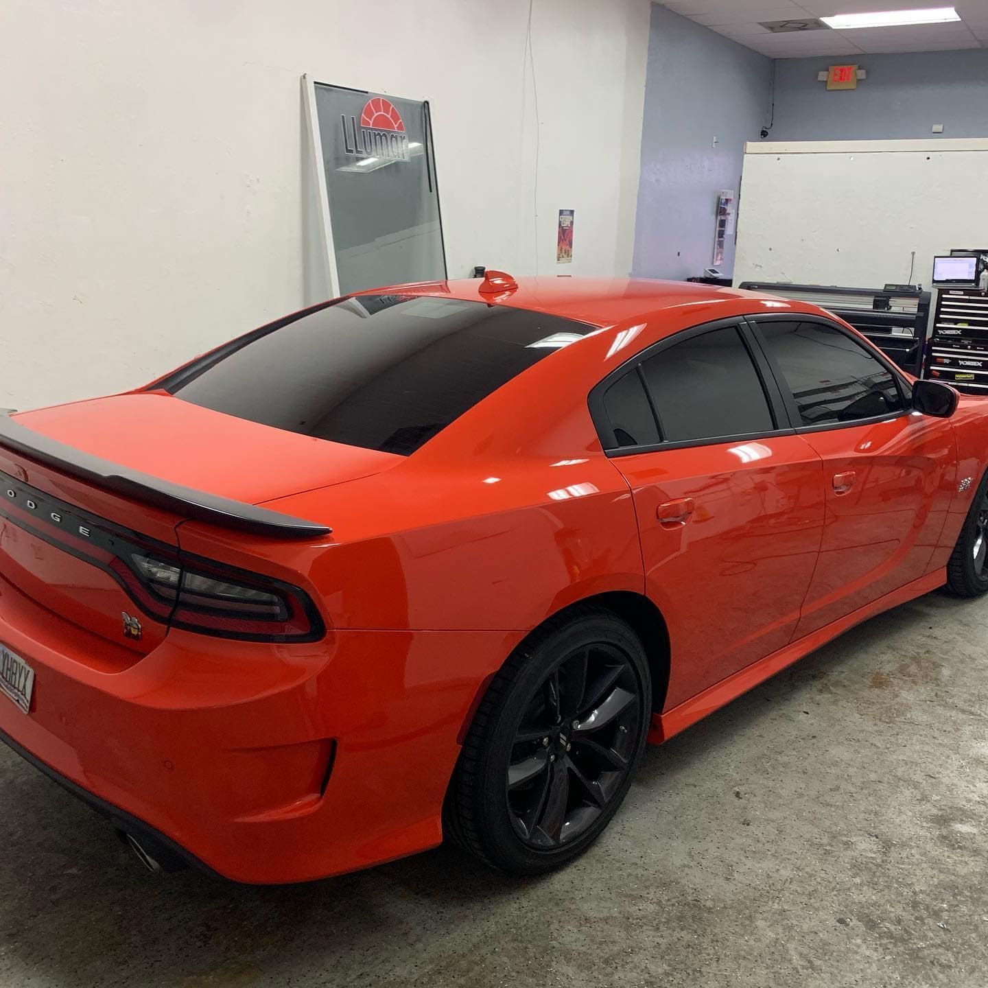 Red sports sedan with black wheels parked in a garage.