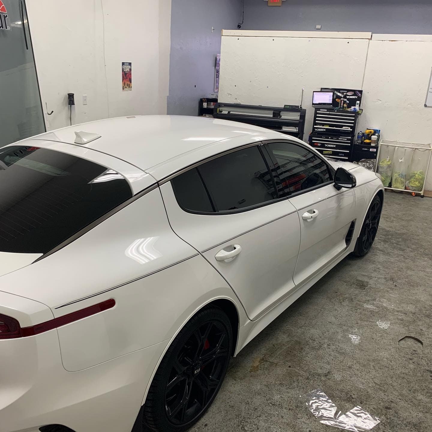 White sedan parked in a garage, viewed from the rear side.