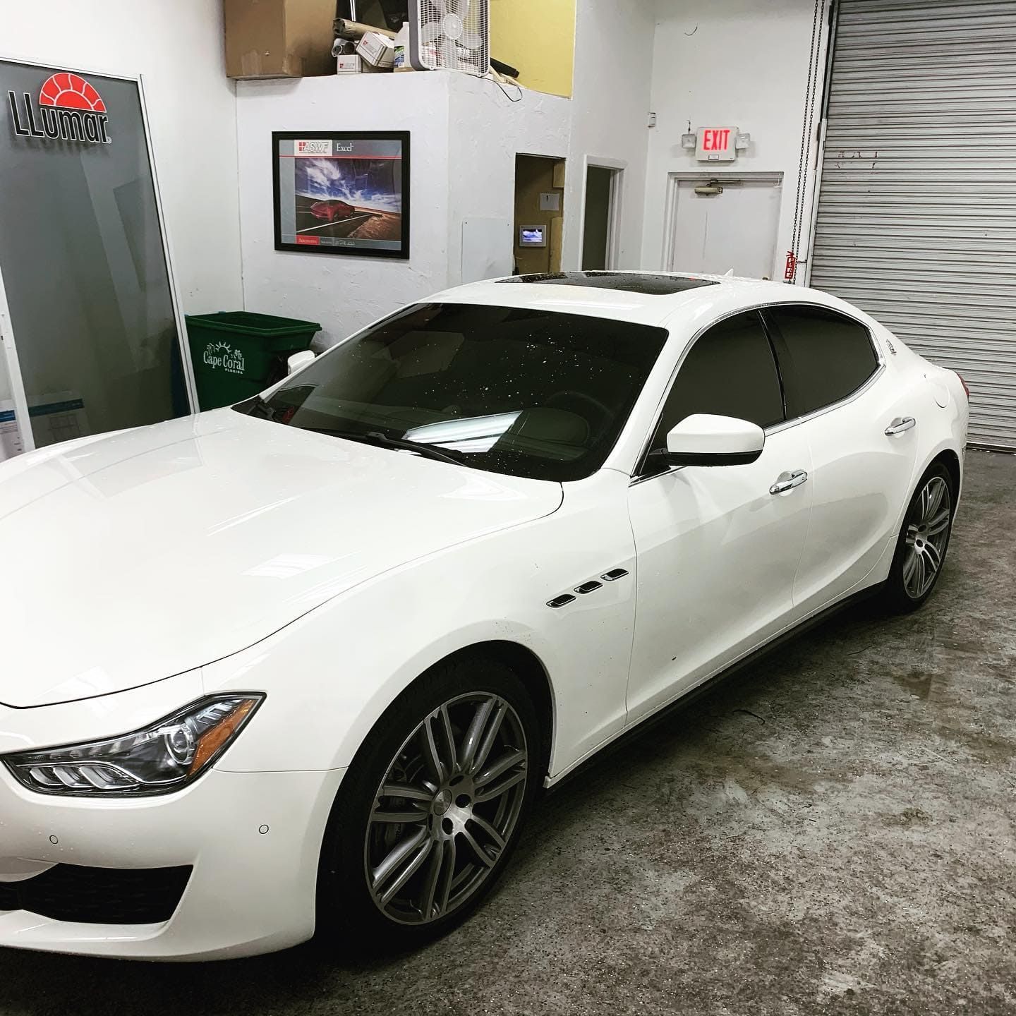 White sports coupe parked in a garage, viewed from the front-left angle.