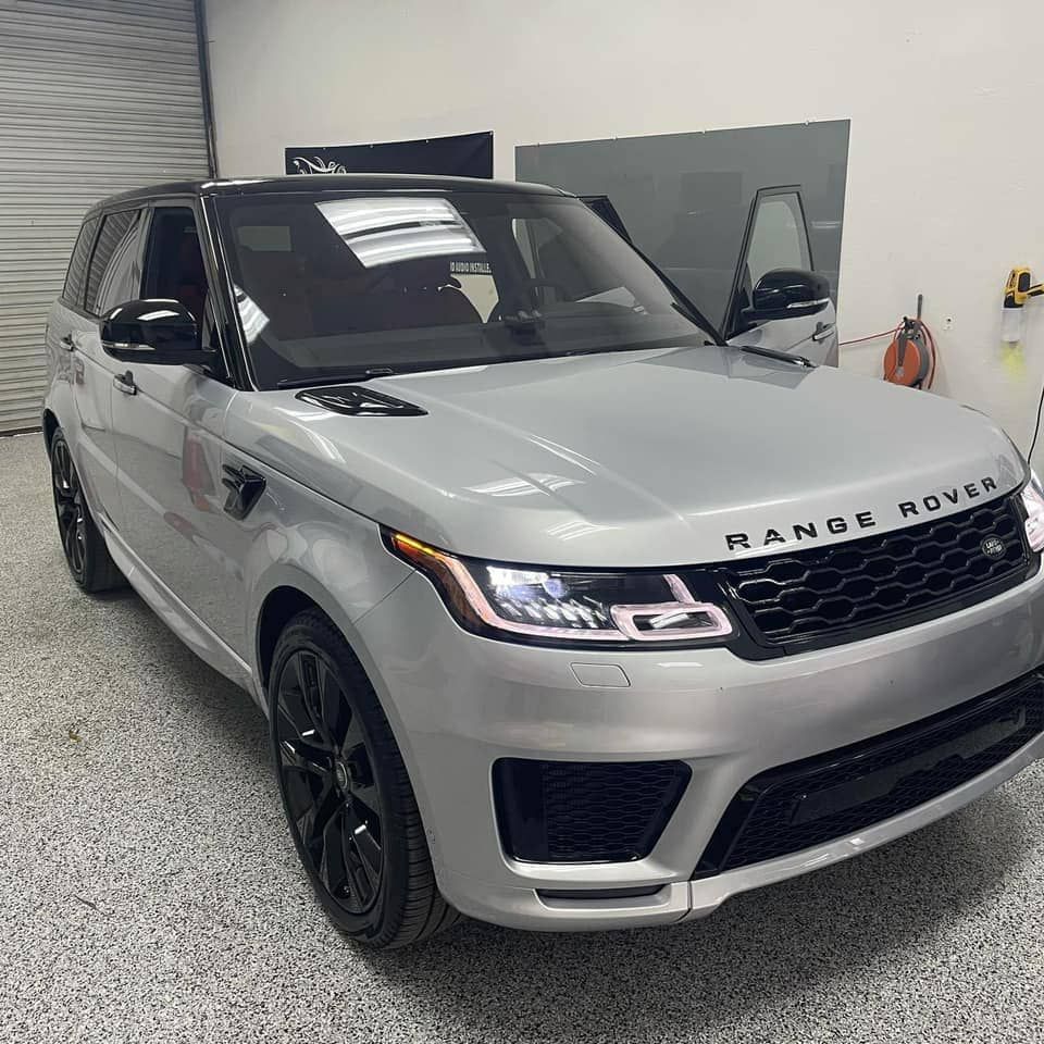 Silver Range Rover SUV parked indoors in a garage, front view with driver door open