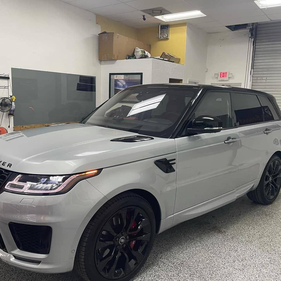 Silver SUV with black roof and wheels parked inside a garage-like workshop room
