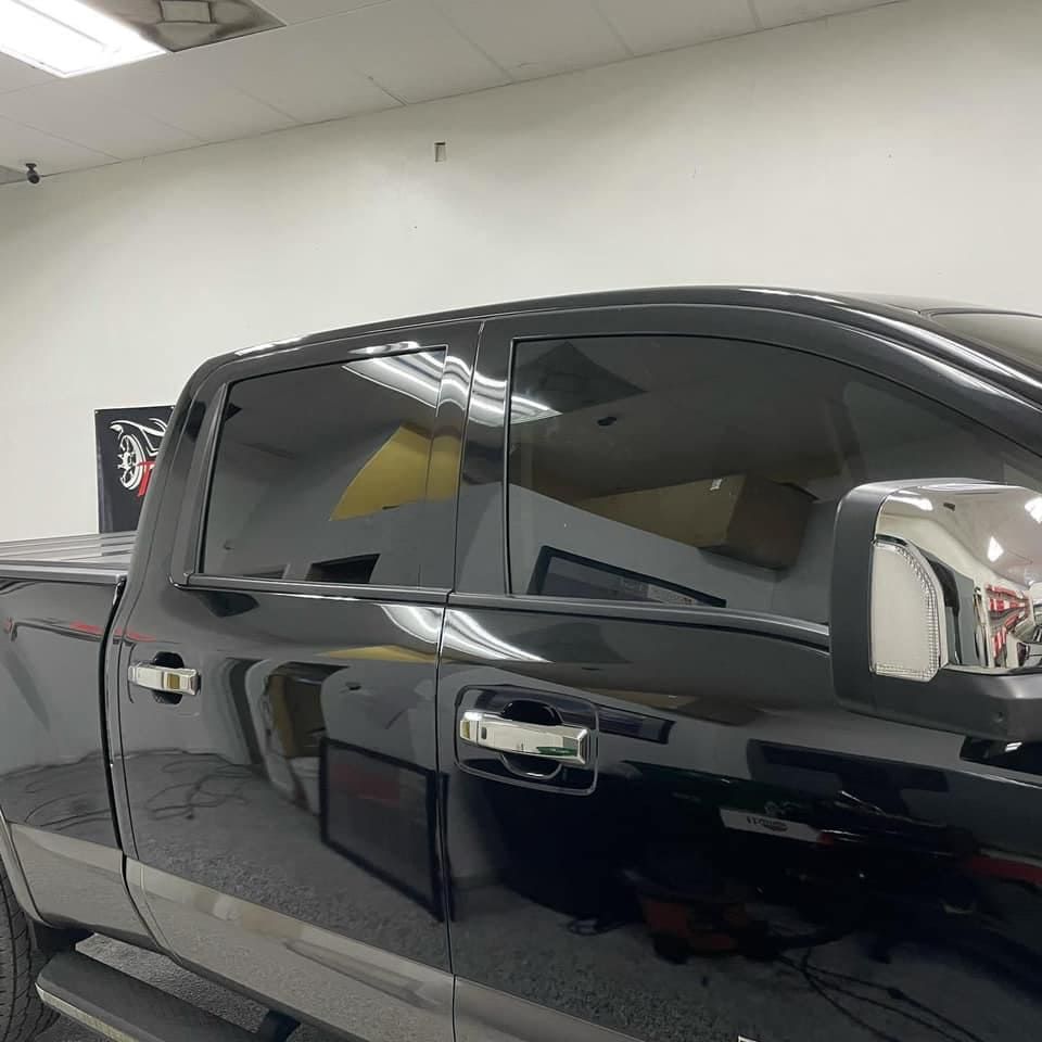 Black pickup truck parked indoors, side view with tinted windows and chrome mirrors