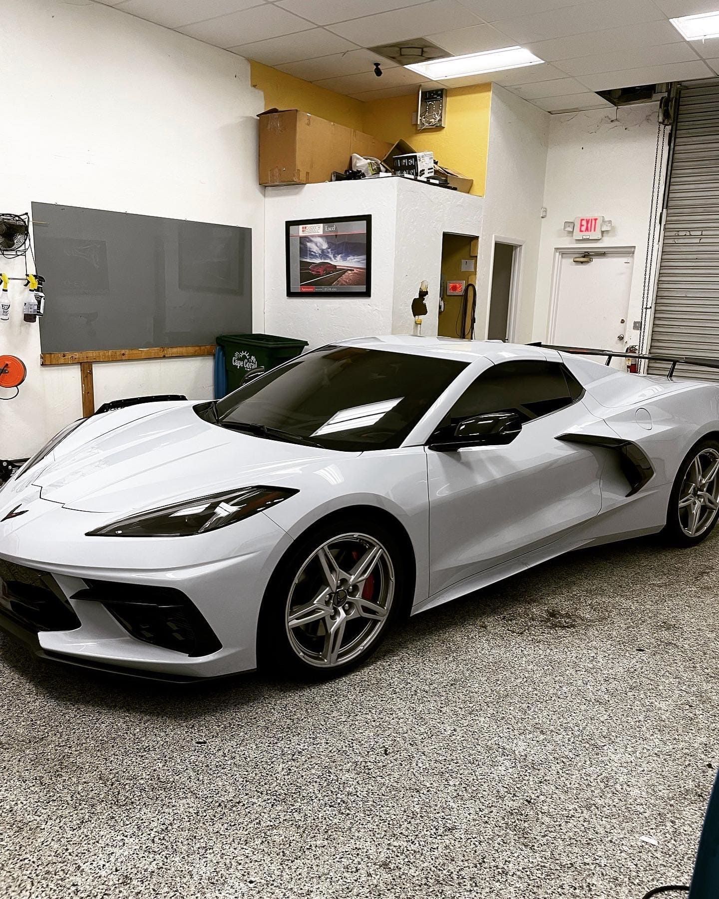 Silver sports car parked in a garage with gray walls and speckled flooring